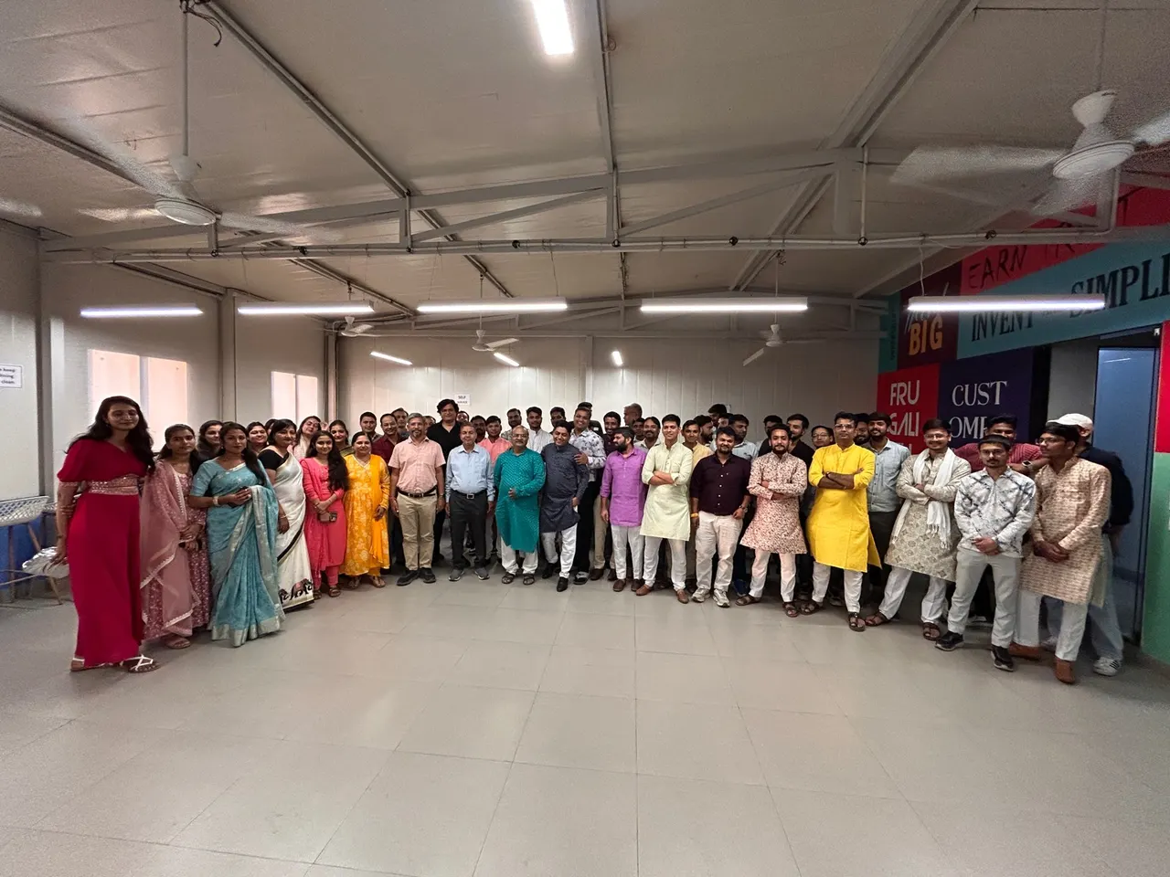 SWIL team gathered in the office hall, dressed in colourful traditional attire, facing the camera.